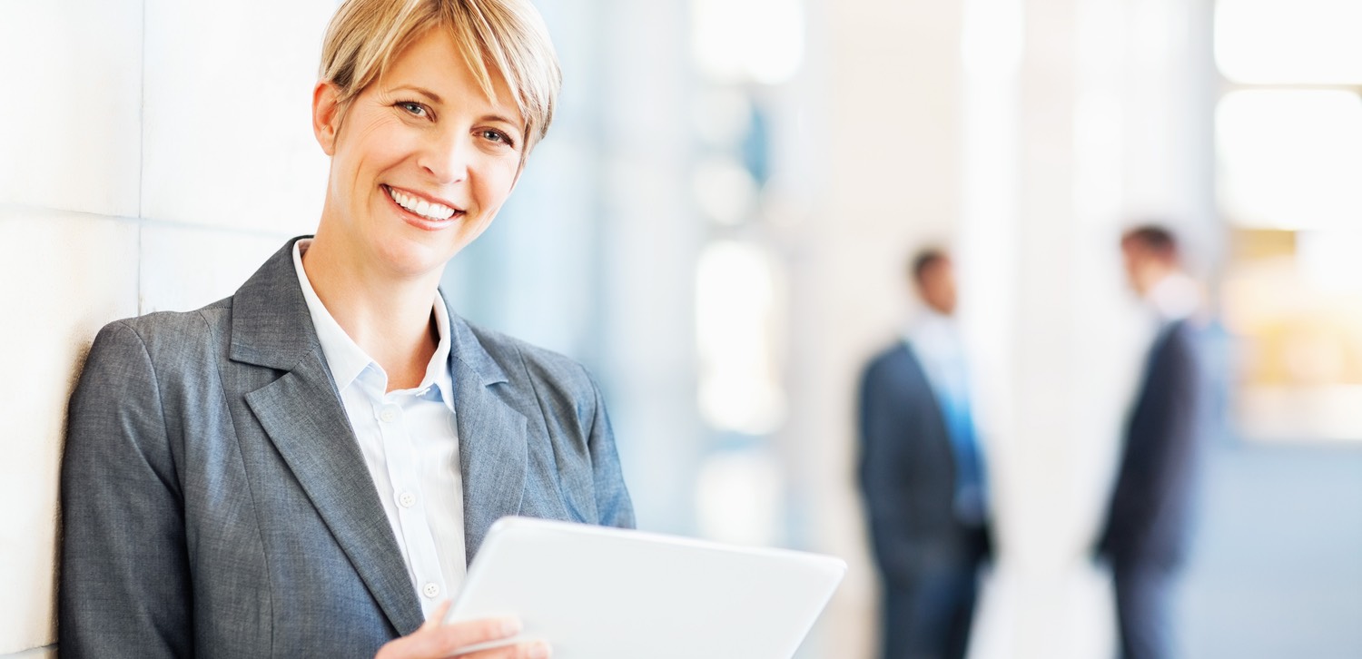 Businessfrau mit einem Tablet in der Hand blickt in die Kamera.